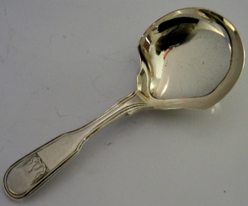A Victorian sterling silver tea caddy spoon featuring a broad shovel-shaped bowl and an engraved crest on the handle. View II