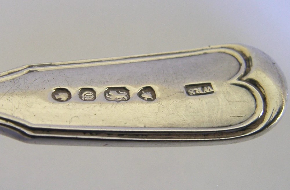 A Victorian sterling silver tea caddy spoon featuring a broad shovel-shaped bowl and an engraved crest on the handle. View V