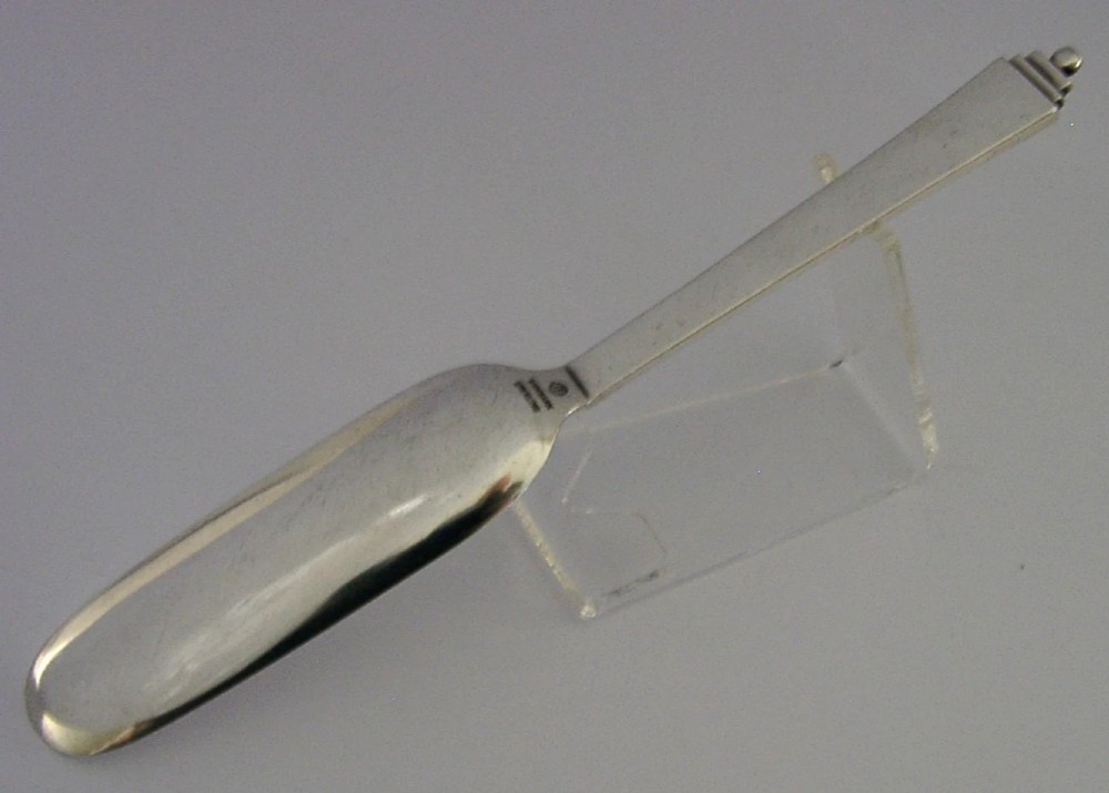 A sterling silver Stilton cheese scoop featuring a tapered handle ending in a stepped pyramid finial. View VI