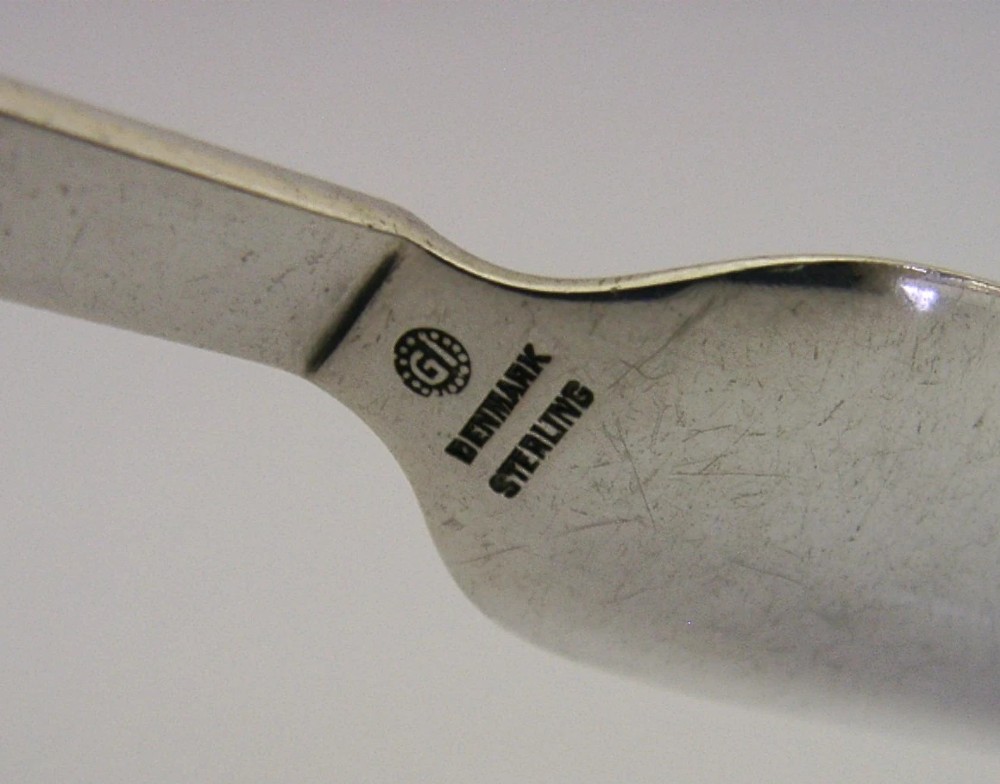 A sterling silver Stilton cheese scoop featuring a tapered handle ending in a stepped pyramid finial. View VII