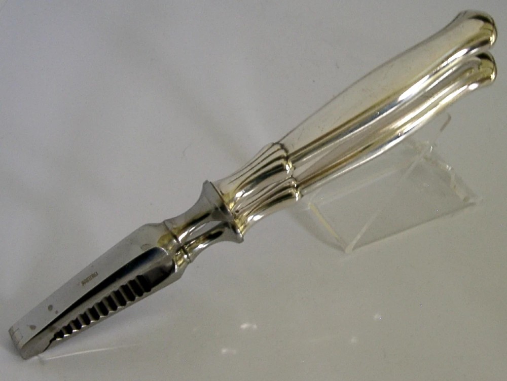 A pair of mid-century German nutcrackers featuring smooth silver handles and serrated metal jaws connected by a central hinge. View II