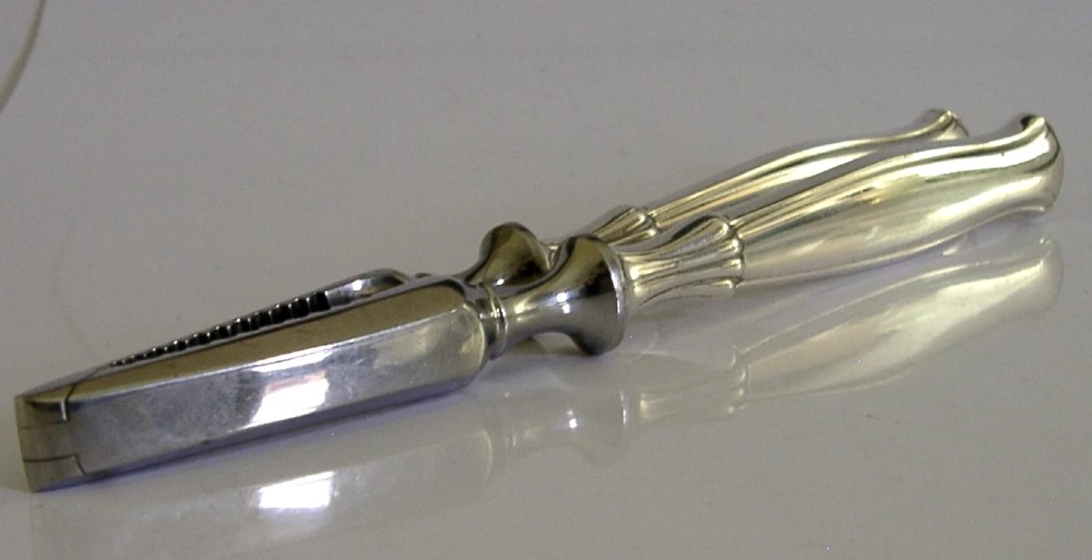 A pair of mid-century German nutcrackers featuring smooth silver handles and serrated metal jaws connected by a central hinge. View V
