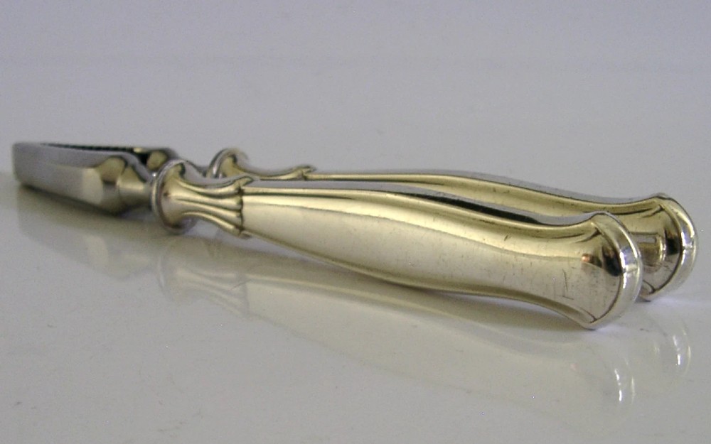 A pair of mid-century German nutcrackers featuring smooth silver handles and serrated metal jaws connected by a central hinge. View VI