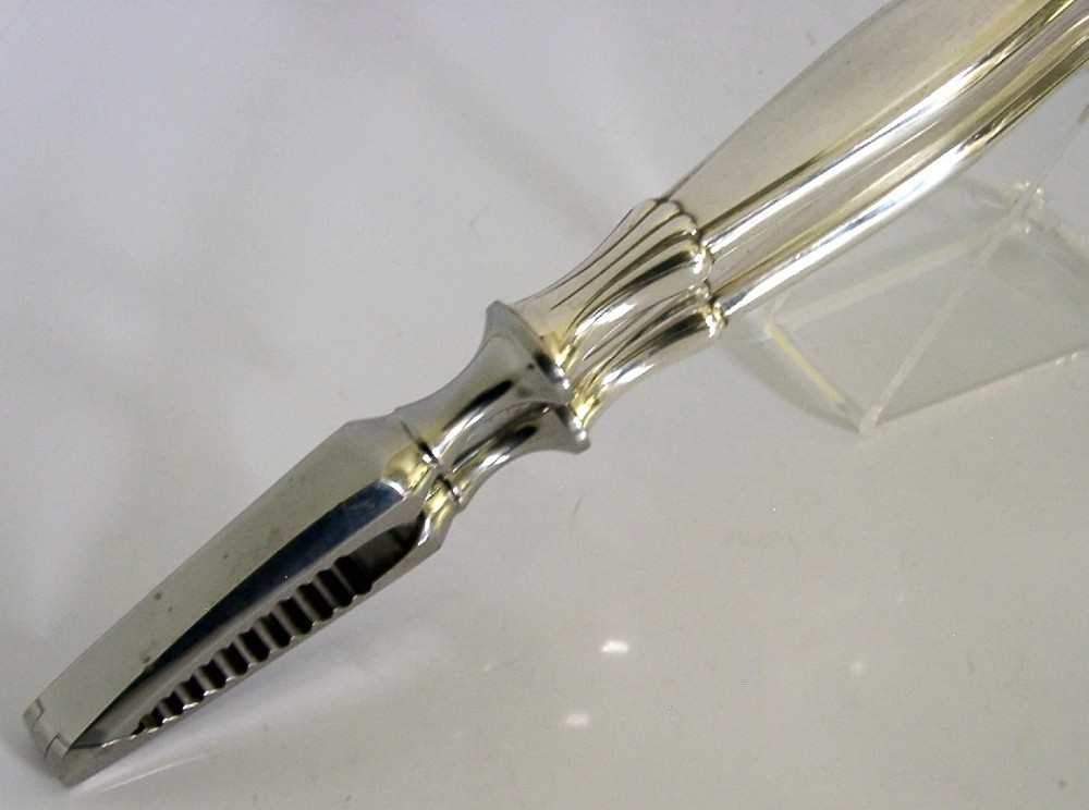 A pair of mid-century German nutcrackers featuring smooth silver handles and serrated metal jaws connected by a central hinge. View VII