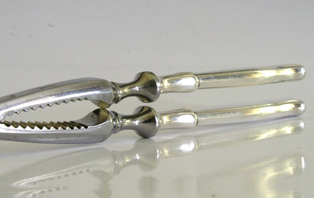 A pair of mid-century German nutcrackers featuring smooth silver handles and serrated metal jaws connected by a central hinge. View VIII