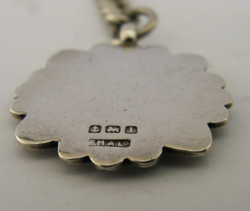 A solid sterling silver double Albert watch chain featuring curb links, a T-bar, two swivel clasps, and a decorative shield fob. View IX