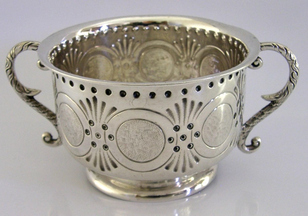 An Edwardian sterling silver twin-handled porringer cup with chased oval panels, an engraved monogram, and ornate scroll handles. View II