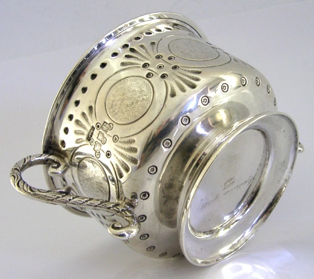 An Edwardian sterling silver twin-handled porringer cup with chased oval panels, an engraved monogram, and ornate scroll handles. View III