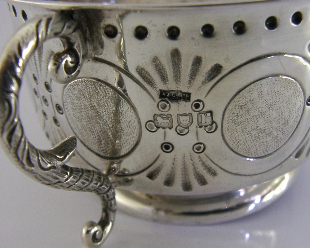 An Edwardian sterling silver twin-handled porringer cup with chased oval panels, an engraved monogram, and ornate scroll handles. View VII