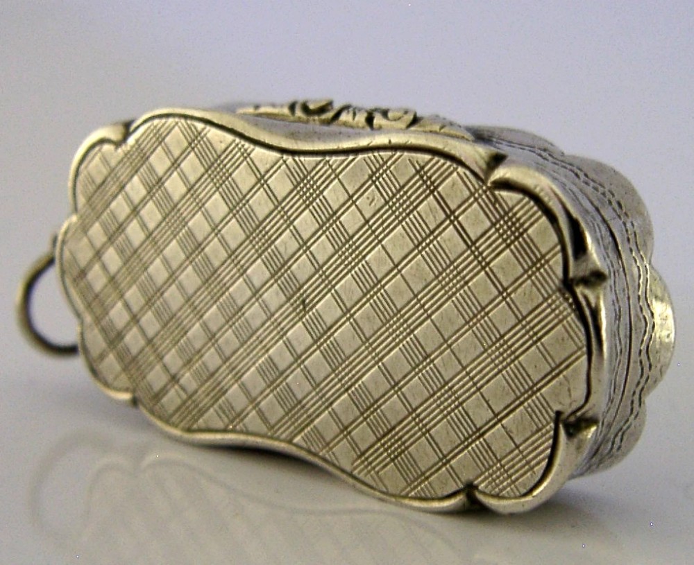 An antique Victorian sterling silver vinaigrette box featuring a shaped lobed outline, engine-turned geometric engraving, and a central engraved monogram cartouche. View IV