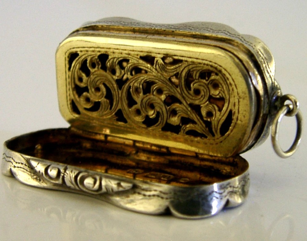 An antique Victorian sterling silver vinaigrette box featuring a shaped lobed outline, engine-turned geometric engraving, and a central engraved monogram cartouche. View V