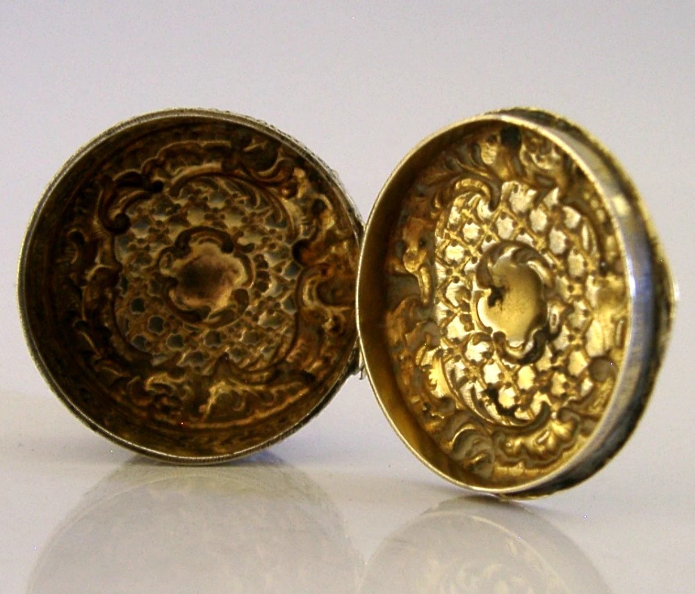 A circular French solid silver pill box with Rococo Revival lattice and floral scroll embossing. View II