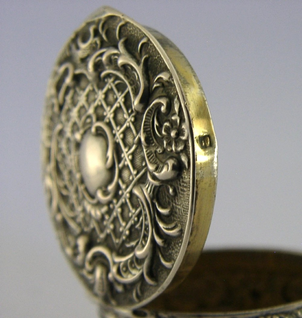 A circular French solid silver pill box with Rococo Revival lattice and floral scroll embossing. View VII