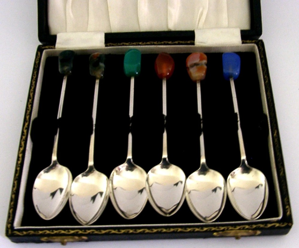 A cased set of six sterling silver coffee spoons with assorted colourful polished agate finials arranged in a dark lined presentation box.