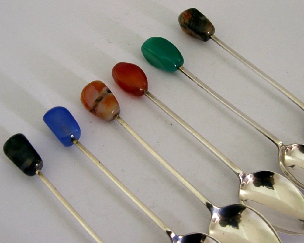 A cased set of six sterling silver coffee spoons with assorted colourful polished agate finials arranged in a dark lined presentation box. View V