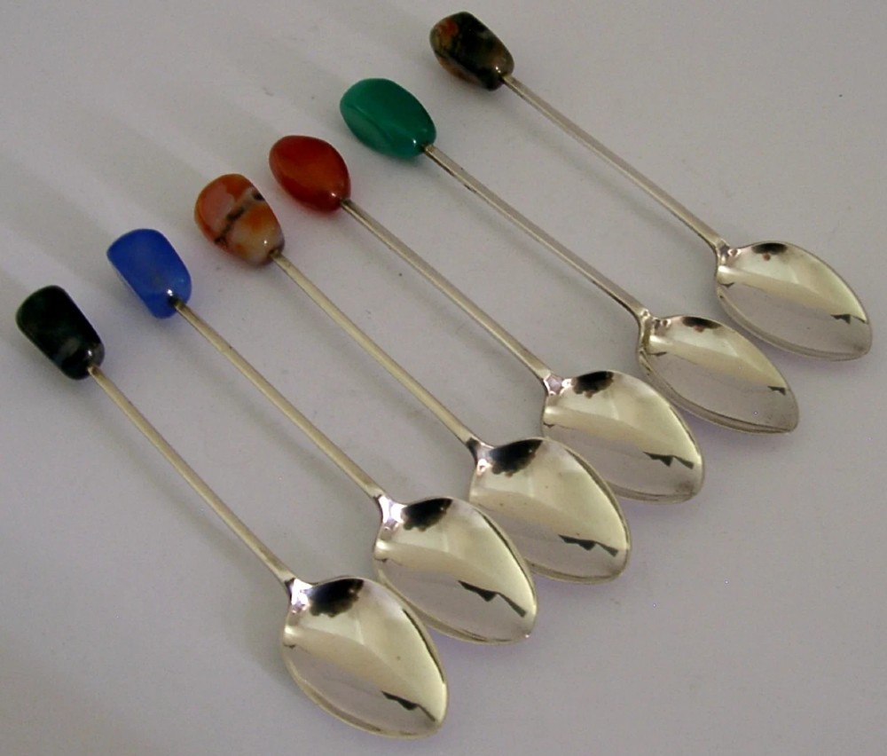 A cased set of six sterling silver coffee spoons with assorted colourful polished agate finials arranged in a dark lined presentation box. View VI