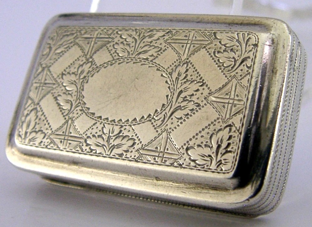 An open rectangular Georgian sterling silver vinaigrette box displaying an engraved exterior and a pierced gold-gilded inner grille featuring floral leaf patterns. View VI