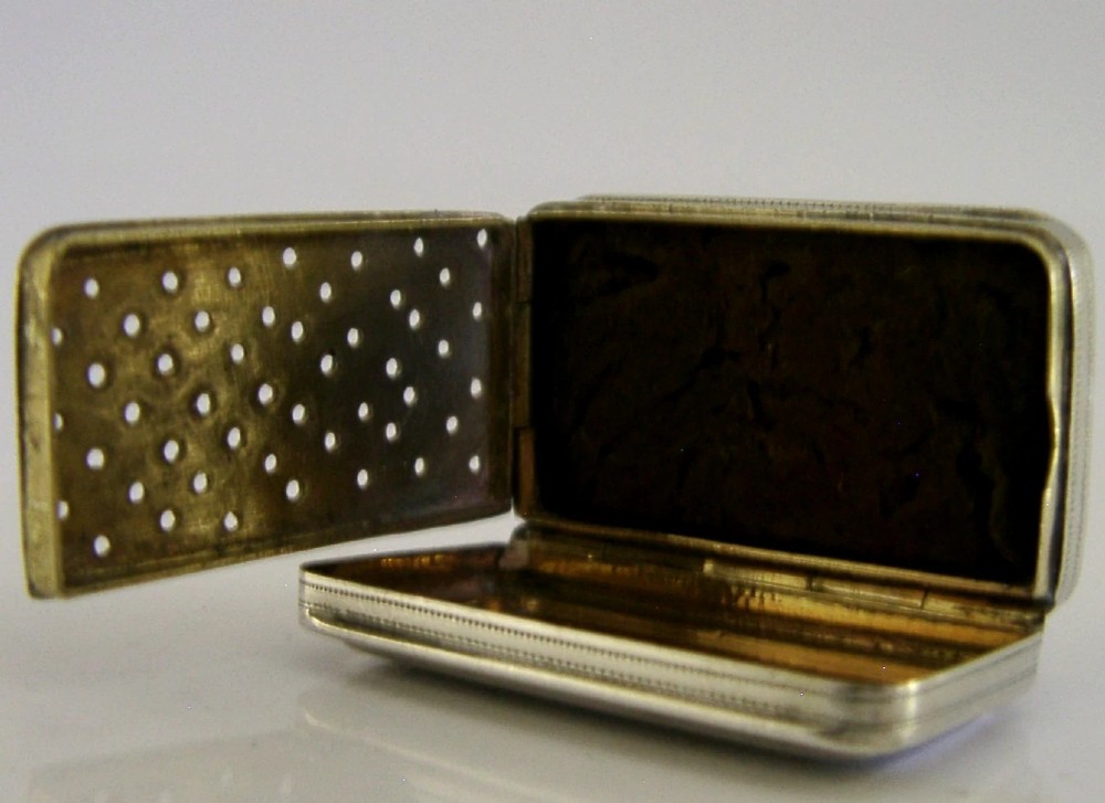 An open rectangular Georgian sterling silver vinaigrette box displaying an engraved exterior and a pierced gold-gilded inner grille featuring floral leaf patterns. View VIII