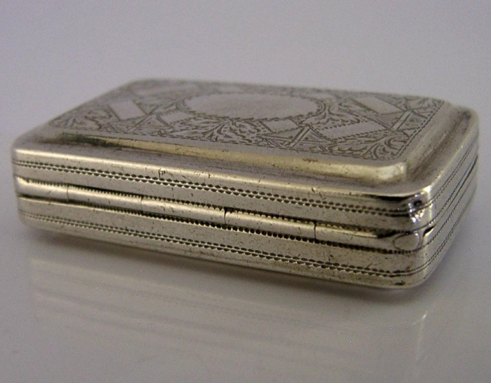 An open rectangular Georgian sterling silver vinaigrette box displaying an engraved exterior and a pierced gold-gilded inner grille featuring floral leaf patterns. View XI