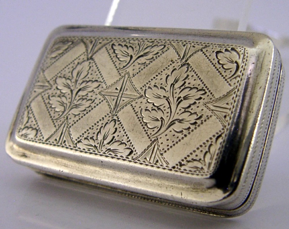An open rectangular Georgian sterling silver vinaigrette box displaying an engraved exterior and a pierced gold-gilded inner grille featuring floral leaf patterns. View XII