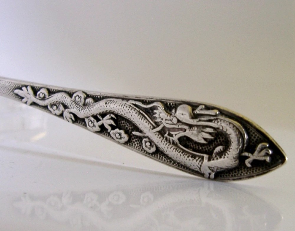 An antique silver serving ladle featuring a rounded circular bowl and a detailed dragon relief chased along the handle. View II