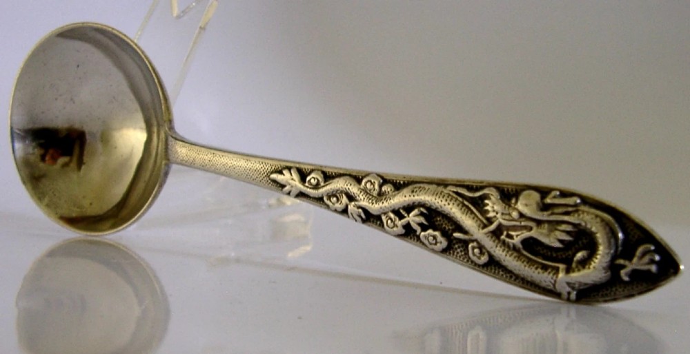 An antique silver serving ladle featuring a rounded circular bowl and a detailed dragon relief chased along the handle. View III