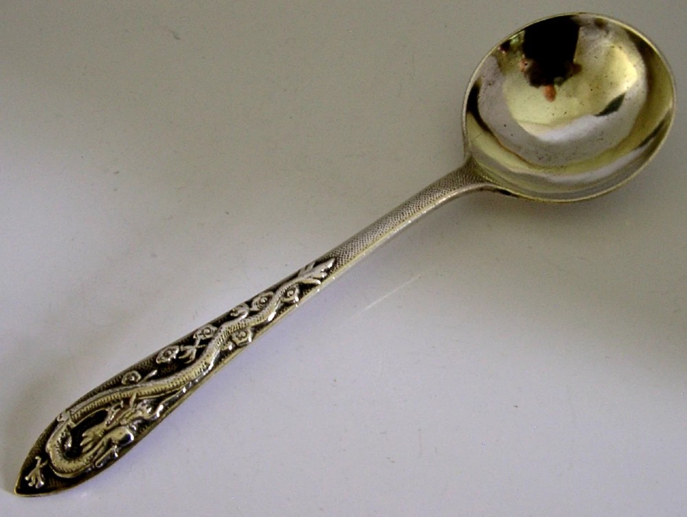 An antique silver serving ladle featuring a rounded circular bowl and a detailed dragon relief chased along the handle. View VI