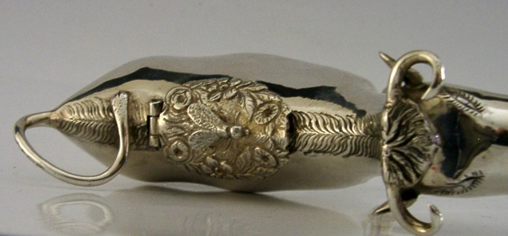 A sterling silver novelty cow creamer featuring a hollow cast body, a hinged lid decorated with floral motifs on the back, and a looped tail handle. View III