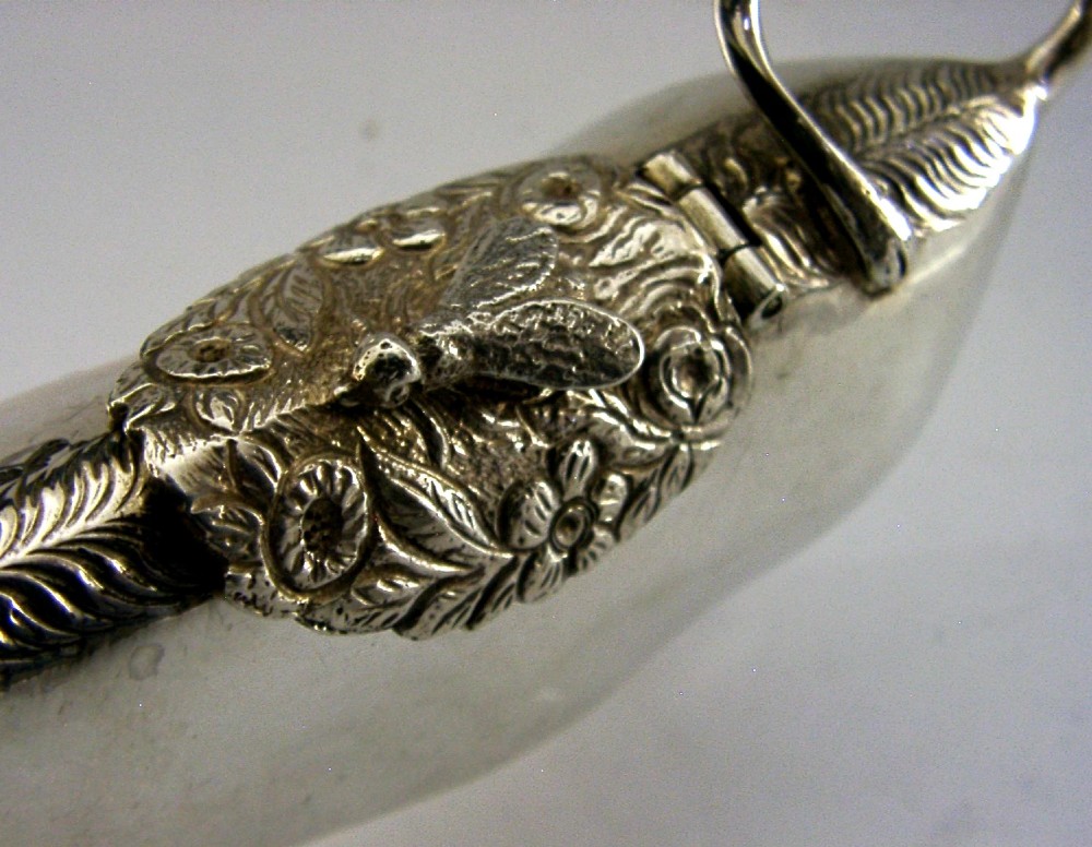 A sterling silver novelty cow creamer featuring a hollow cast body, a hinged lid decorated with floral motifs on the back, and a looped tail handle. View V