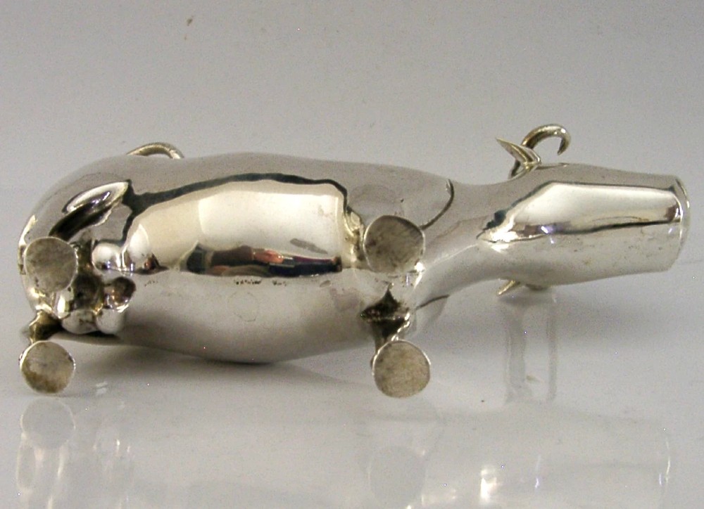 A sterling silver novelty cow creamer featuring a hollow cast body, a hinged lid decorated with floral motifs on the back, and a looped tail handle. View IX
