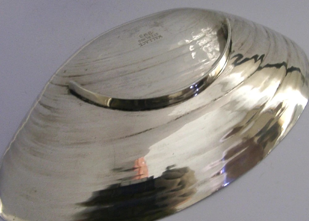 A sterling silver dish crafted in the shape of an open clam shell with visible concentric ridged textures and polished metallic surface. View IV