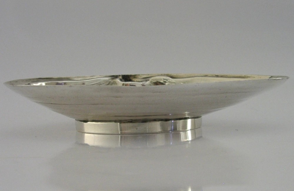 A sterling silver dish crafted in the shape of an open clam shell with visible concentric ridged textures and polished metallic surface. View VI