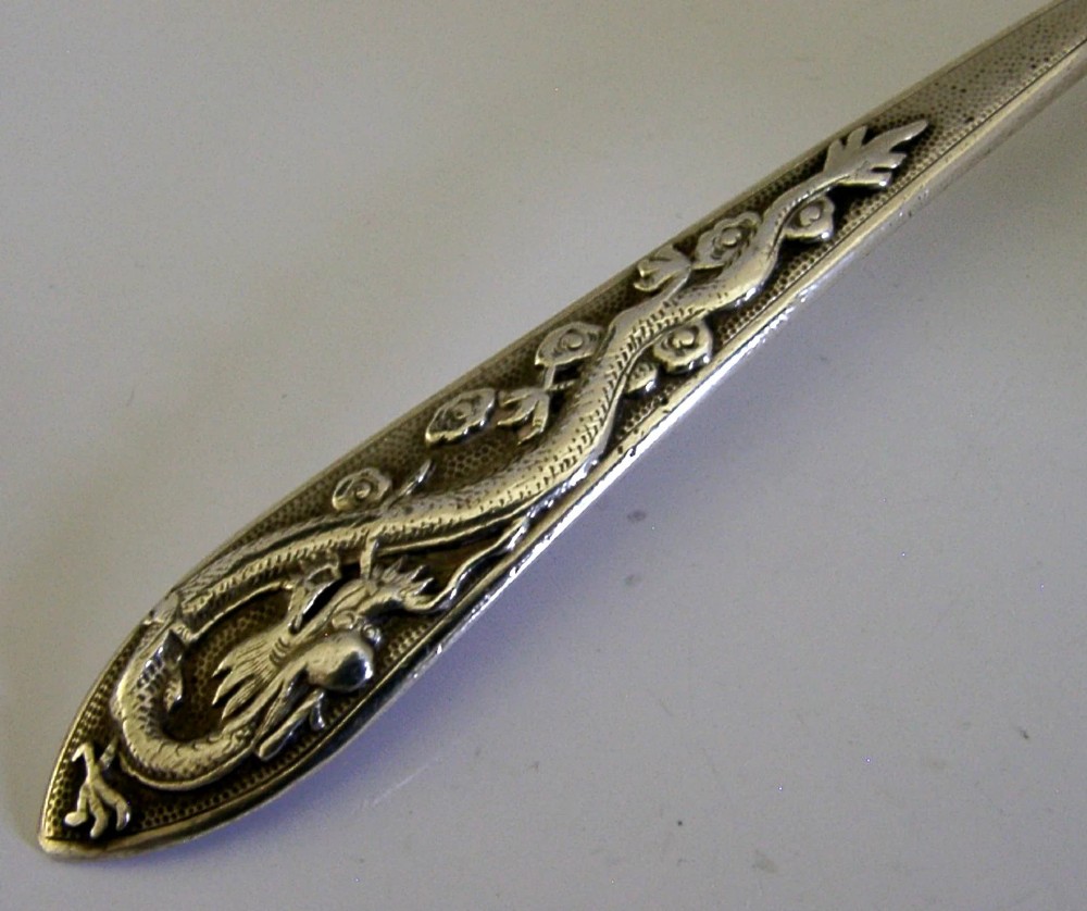 An antique Chinese export silver spoon featuring a detailed chased dragon design sculpted along its handle and a polished oval bowl. View III