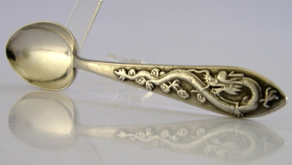 An antique Chinese export silver spoon featuring a detailed chased dragon design sculpted along its handle and a polished oval bowl. View IV