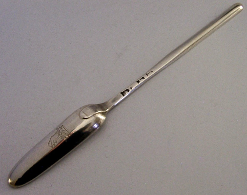 A Georgian sterling silver marrow scoop featuring an engraved family crest on the elongated scoop and stamped hallmarks along the narrow handle.