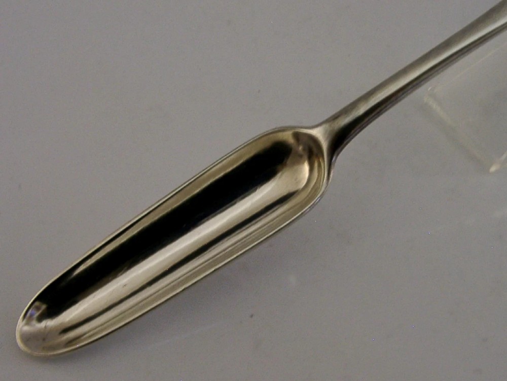 A Georgian sterling silver marrow scoop featuring an engraved family crest on the elongated scoop and stamped hallmarks along the narrow handle. View VI