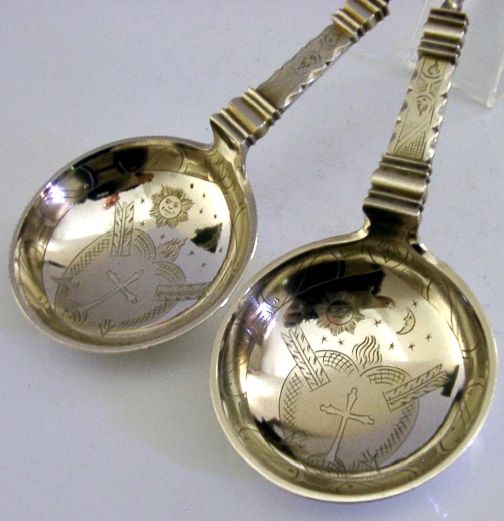 A pair of antique Norwegian silver serving spoons featuring round engraved bowls, twisted wire stems, and decorative knop finials. View II