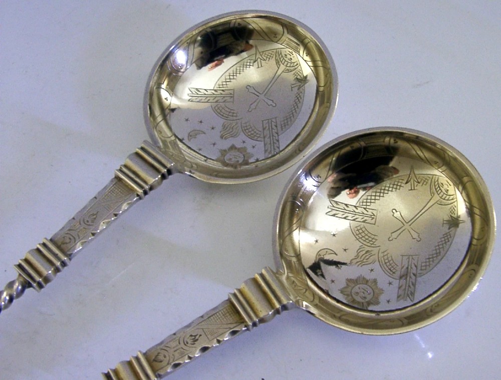 A pair of antique Norwegian silver serving spoons featuring round engraved bowls, twisted wire stems, and decorative knop finials. View III