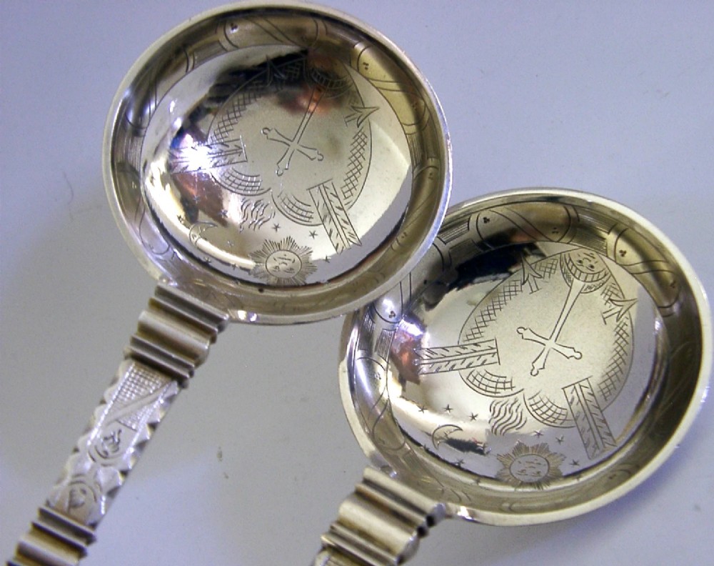 A pair of antique Norwegian silver serving spoons featuring round engraved bowls, twisted wire stems, and decorative knop finials. View VII
