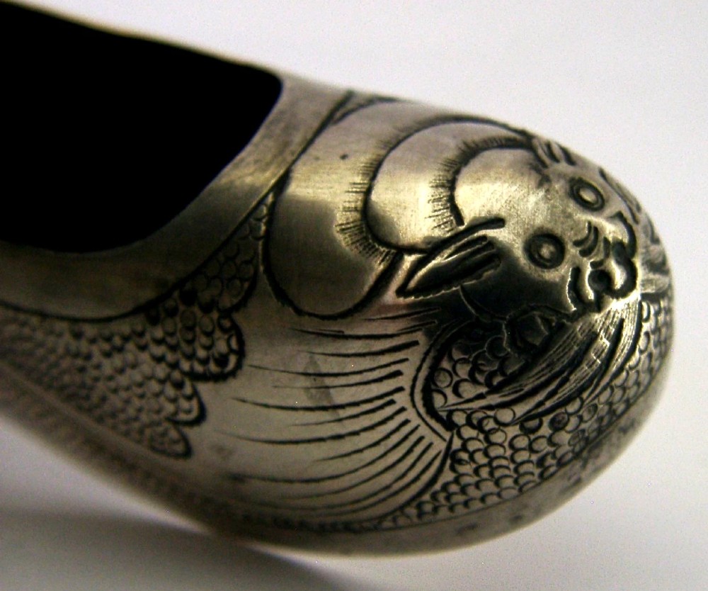 An antique Chinese export silver novelty pin cushion formed in the shape of a traditional slipper, featuring chased bat motifs and textured surface decoration. View III
