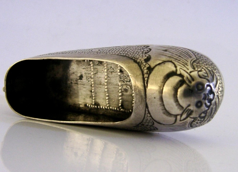 An antique Chinese export silver novelty pin cushion formed in the shape of a traditional slipper, featuring chased bat motifs and textured surface decoration. View V