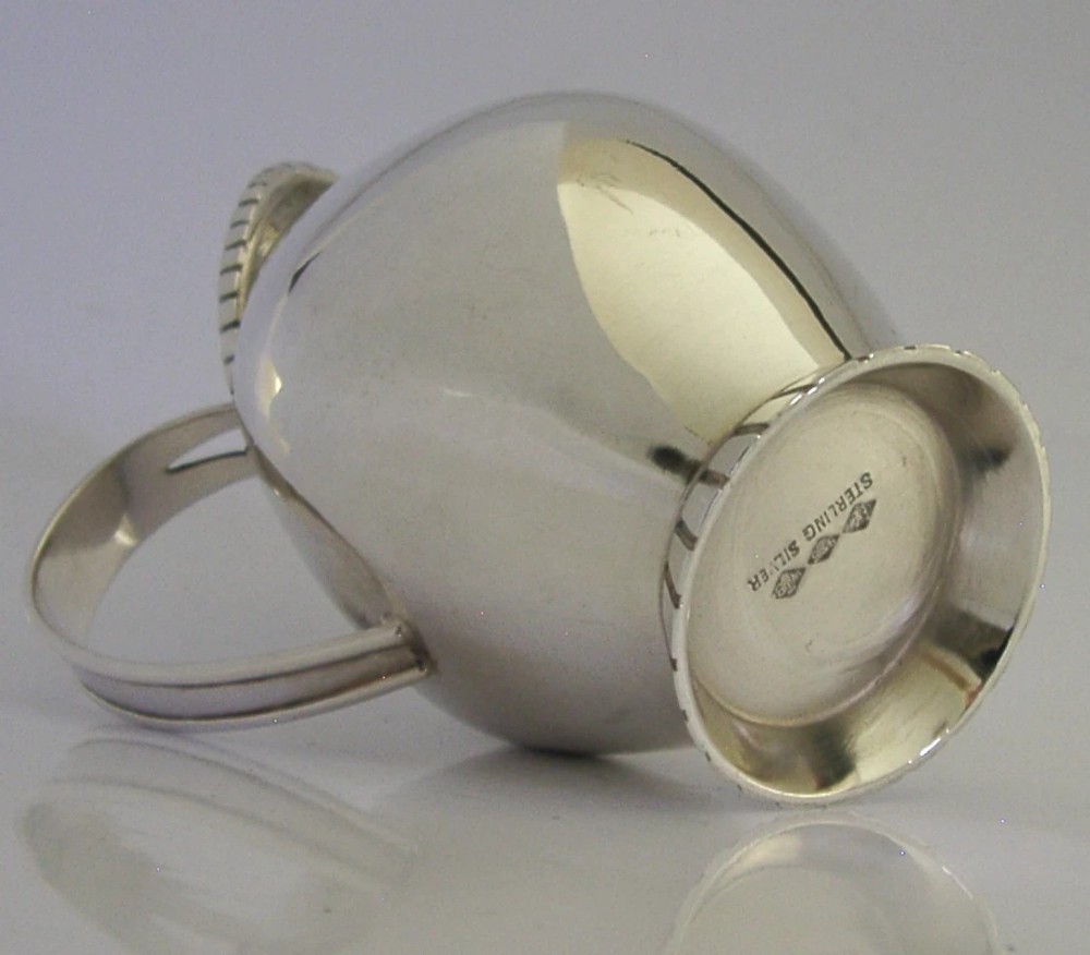 A pear-shaped mid-century sterling silver cream jug featuring a fluted rim, a matching fluted foot ring, and a single loop handle. View VI