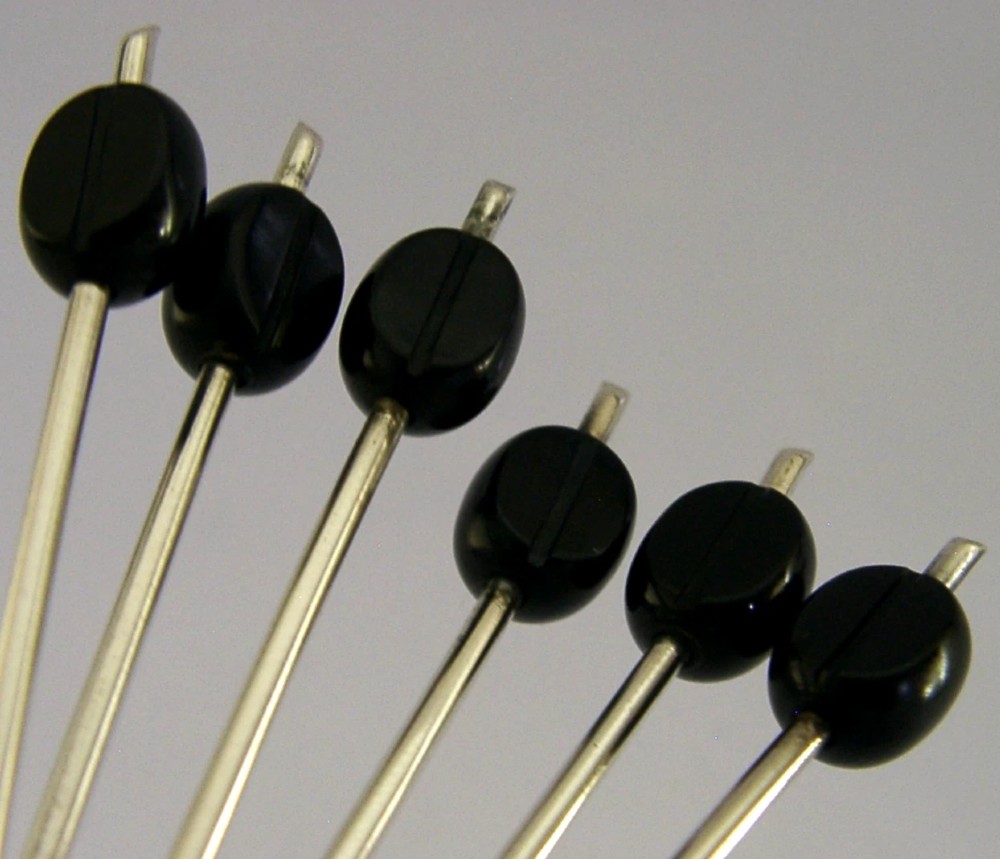 A fitted display case containing six sterling silver coffee spoons with black coffee bean finials and matching sugar tongs. View IV
