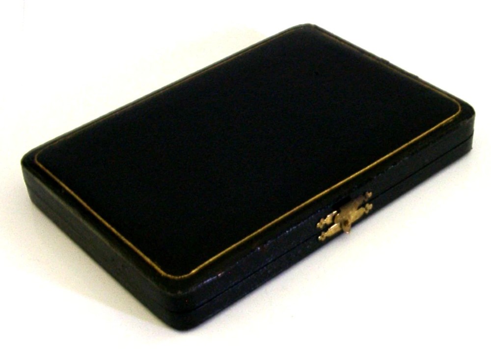A fitted display case containing six sterling silver coffee spoons with black coffee bean finials and matching sugar tongs. View VI