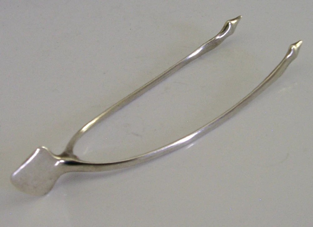A pair of solid sterling silver sugar tongs shaped like a bird wishbone with visible British hallmarks on the upper bridge. View II