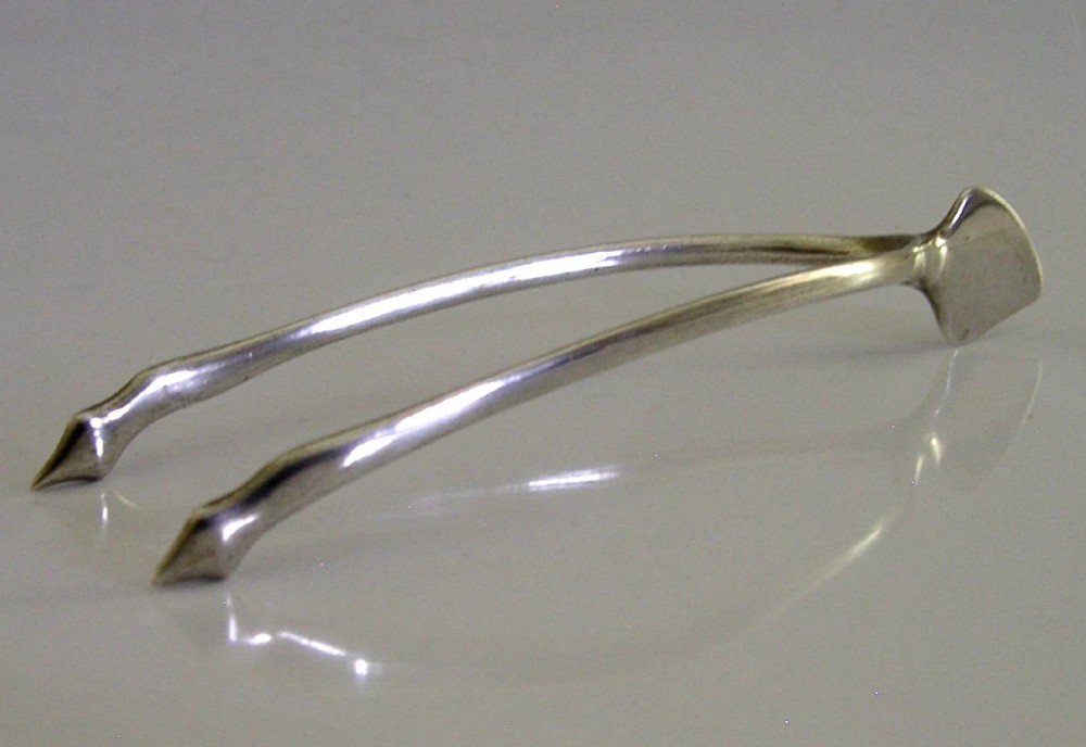 A pair of solid sterling silver sugar tongs shaped like a bird wishbone with visible British hallmarks on the upper bridge. View IV