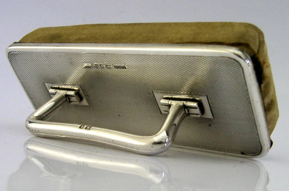 An engine-turned sterling silver nail buffer featuring a folding rectangular handle and English hallmarks, resting on a chamois base. View II