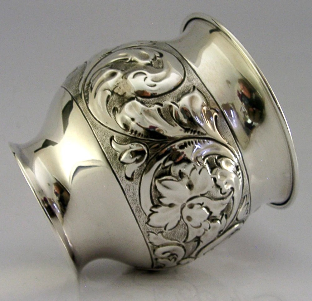 An Edwardian sterling silver fern pot featuring detailed embossed acanthus leaf and scroll decoration around the body with a polished flared rim.