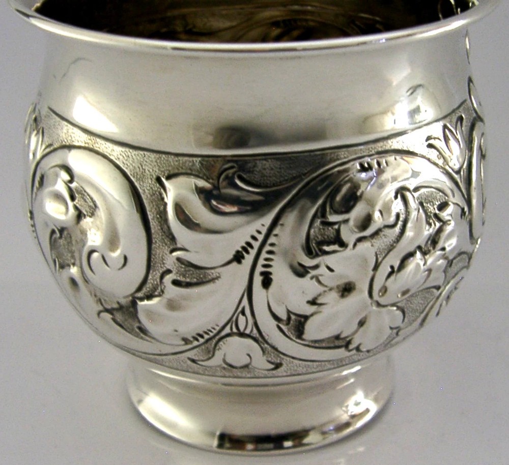An Edwardian sterling silver fern pot featuring detailed embossed acanthus leaf and scroll decoration around the body with a polished flared rim. View II