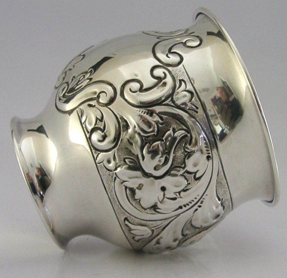 An Edwardian sterling silver fern pot featuring detailed embossed acanthus leaf and scroll decoration around the body with a polished flared rim. View IV